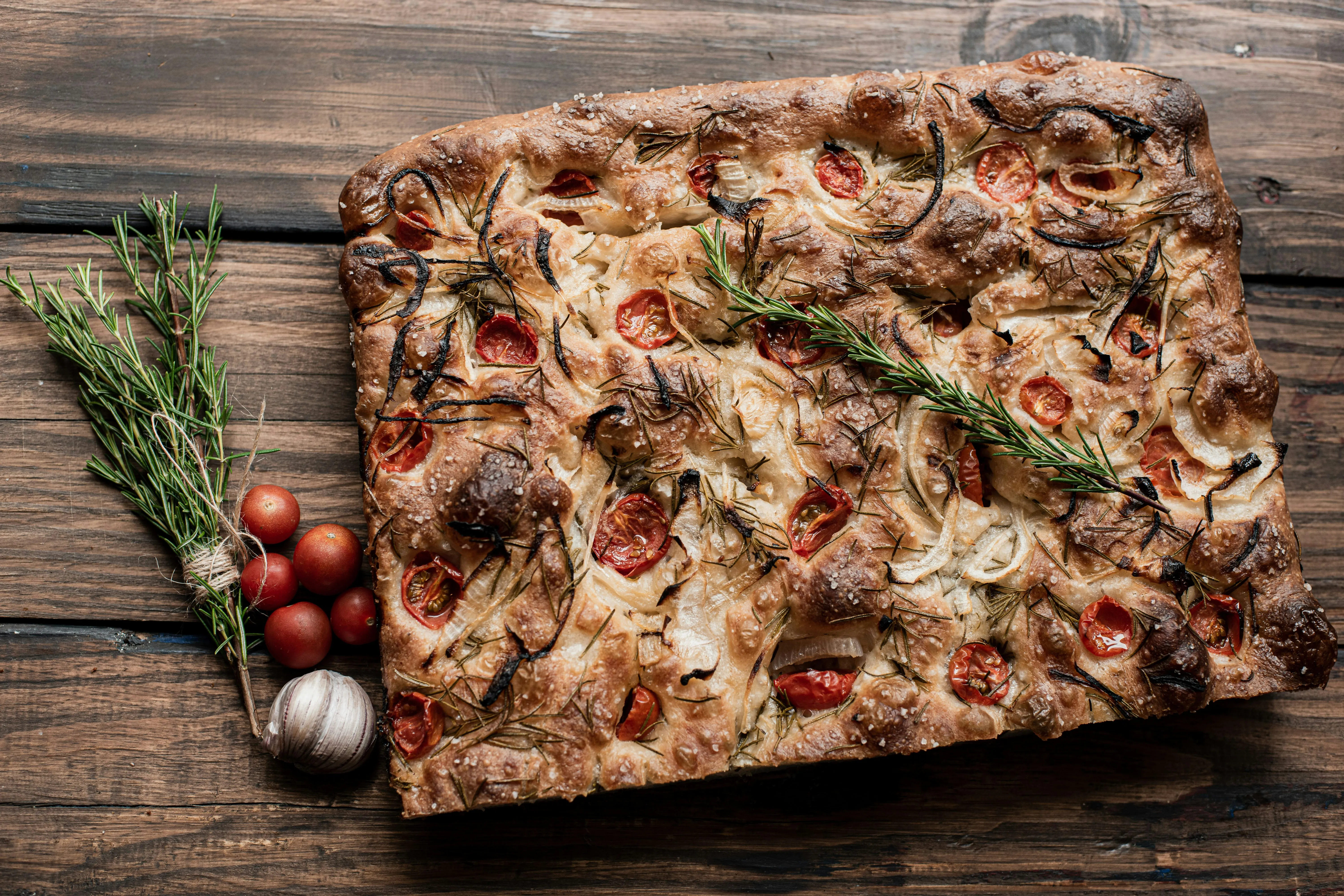 Fertig gebackene Focaccia mit Tomaten, Zwiebeln und Rosmarin